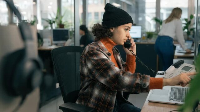 Medium shot focused on a call center agent using voice and video tools integrated in a unified communications bundle surrounded by softly blurred headset and monitors.