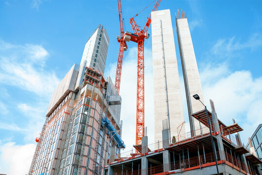 Construction site in city with cranes lifting materials towards new buildings