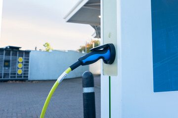 Electric vehicle charging station with plug connected and modern setting during morning light © Iryna