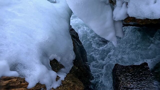 Black Sea in winter: waves strike rocks covered with ice and icicles, and splashes of saline water hit the video camera.