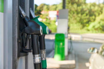 Two fuel pumps at a gas station during the day in a green and outdoor setting © Iryna