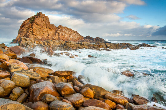 Waves crashing on a rocky shoreline below a prominent coastal rock formation
