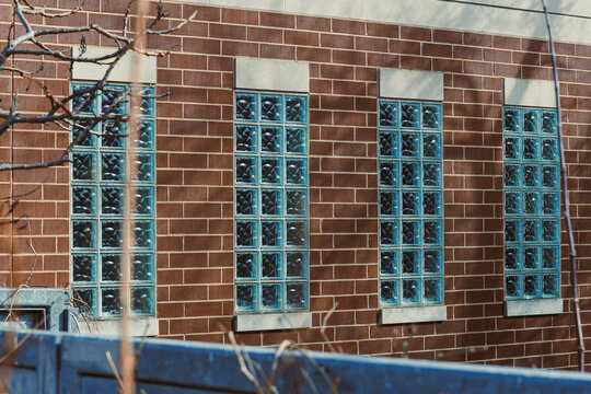 Brick wall with blue glass block windows in an urban setting during daylight hours