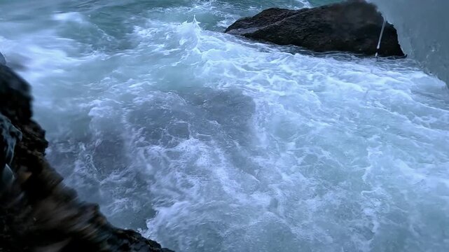 Winter storm in the Black Sea, waves wash over coastal rocks, splashes of foaming saline water at the shoreline