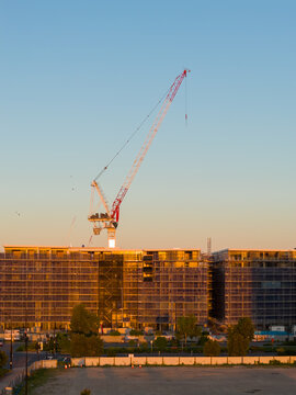Aerial view of a tower crane on top of a highrise builing under construction in golden light