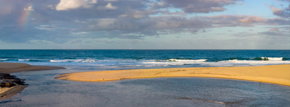 Aerial panorama view of an inland lake flowing round a golden sandy beach then out to sea