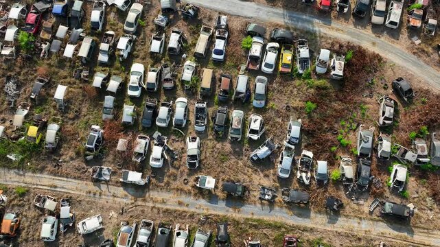 Drone aerial capture of hundreds of deteriorating and crashed vehicles stored in a salvage yard, highlighting the impact of accidents and the retirement of aging automobiles.
