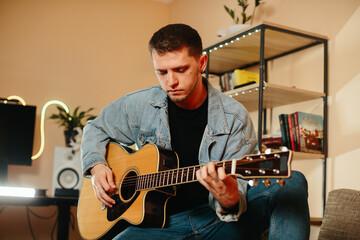 Obraz premium Young musician composing music playing acoustic guitar at home studio