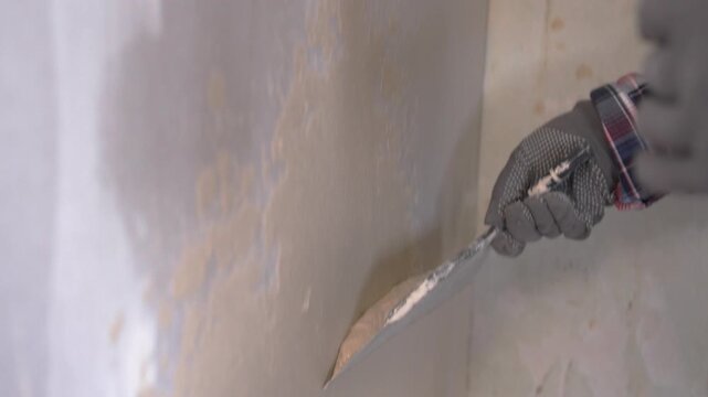 worker using putty knife applying thick patching interior wall.