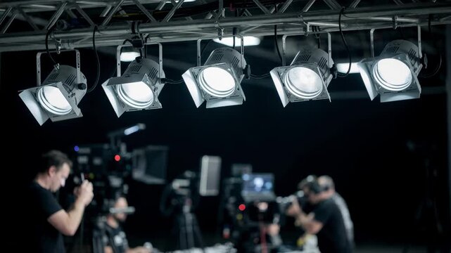 Medium shot of adjustable LED spotlights glowing softly above a blurred film set showcasing energysaving overhead fixtures with DMX control.