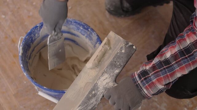 Woman construction worker mixing mortar and plastering wall with putty-knife. DIY housing improvement concept.