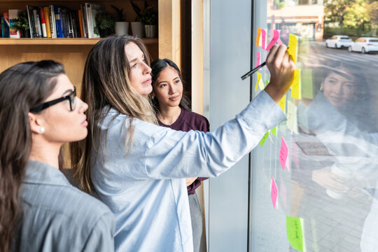 Businesswomen brainstorming strategies with sticky notes