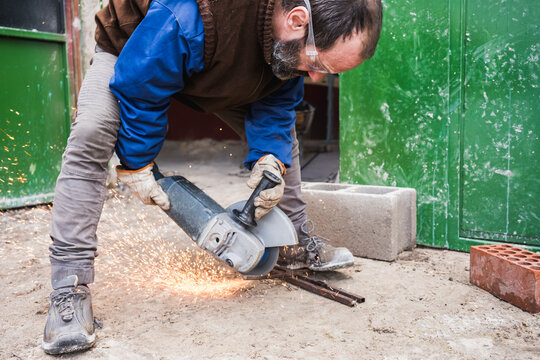 Worker using angle grinder for metal cutting outdoors