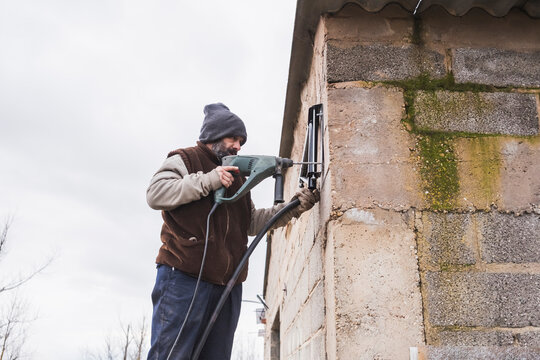 Worker using a power drill on an exterior wall