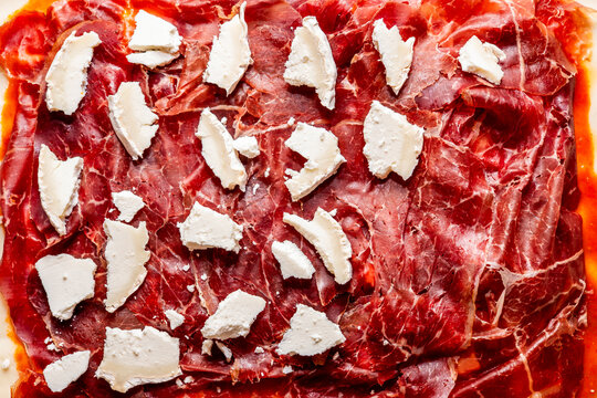 Thinly sliced cured meat garnished with cheese pieces