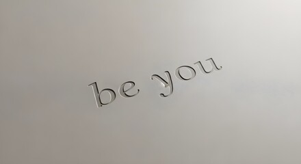 Fototapeta premium Embossed be you message on a gray background with a motivational quote