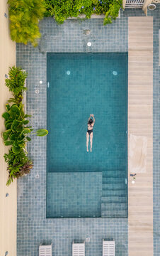 Woman swimming in tranquil summer pool setting