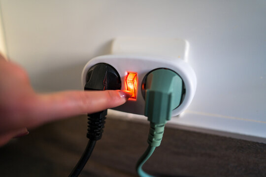 Finger pressing a power switch on an outlet