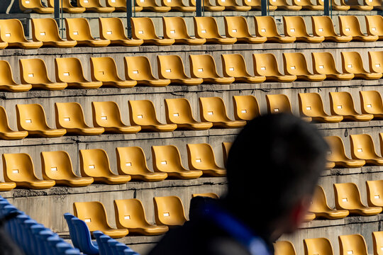 Rows of empty yellow stadium chairs under sunlight
