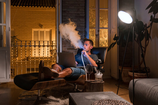 Man smoking hookah in evening at home