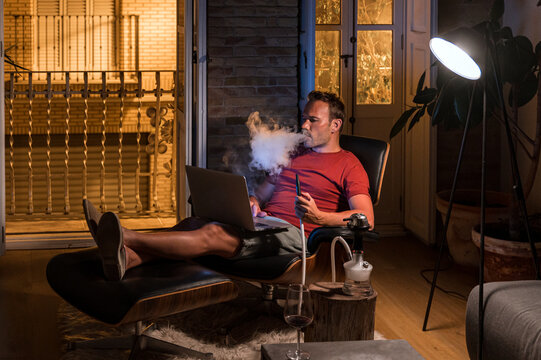 Man smoking hookah in evening at home