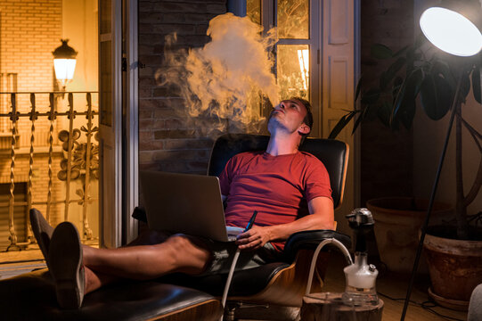 Man smoking hookah in evening at home