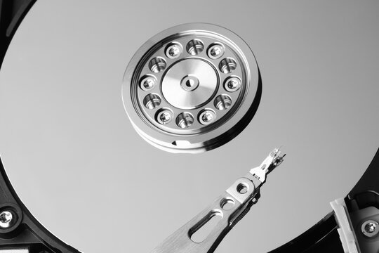 Hard disk drive interior, sleek metallic design. Read-write head hovers near spinning platter. High-tech precision, cold industrial aesthetic. Ideal for tech, innovation, or data storage themes