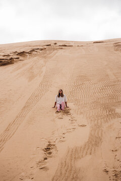 Woman sitting on a sand dune in Walvis Bay, Namibia