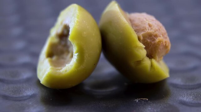 Halved green Olive (Olea europaea) with intact pit rotating 360, cross-section anatomy of mesocarp and endocarp, Food Tech visual.