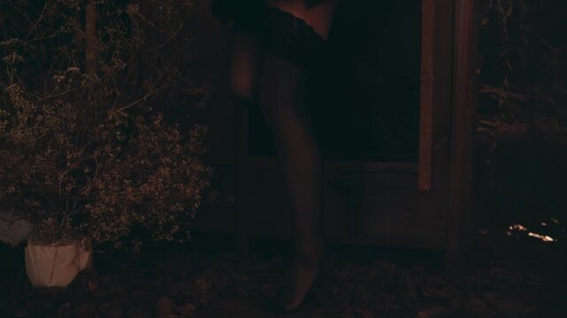Mysterious beautiful woman in a witch costume with black lipstick and a pointy hat emerging from a dark vintage wardrobe in a spooky forest at night, celebrating halloween with magic