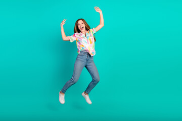 Happy Young Woman Jumping in Casual Outfit Against Turquoise Background