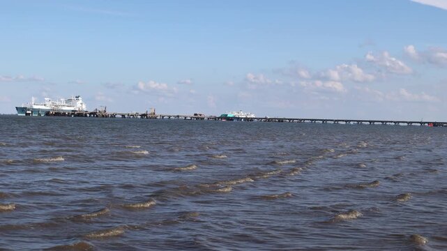 Large liquefied natural gas tanker docked at an industrial pier for loading or unloading