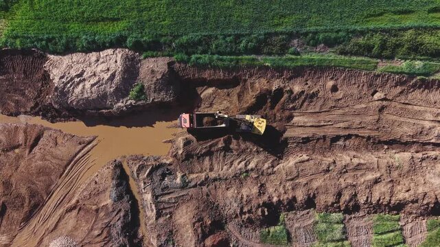 Maquinaria en acci&oacute;n: gr&uacute;a llenando el dumper mientras la cantera se despliega desde el dron