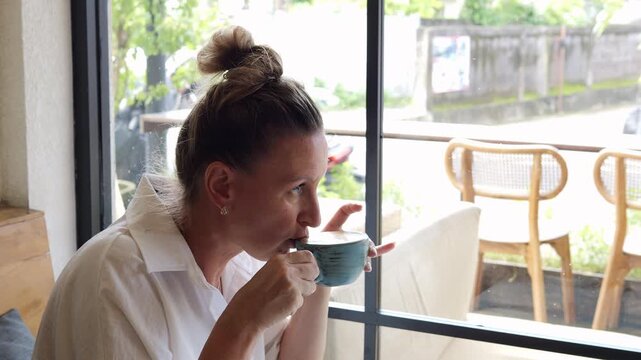 Mindful coffee ritual during busy routine woman enjoying quiet moment by window in modern cafe Break restores focus break supports balance break transforms daily stress into calm reflection 