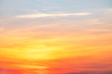 Fototapeta premium Beautiful sunrise sky with vibrant gradient orange and gold colors and soft blue, Clear atmosphere with wispy clouds. Peaceful, perfect for background and copy space, High resolution images