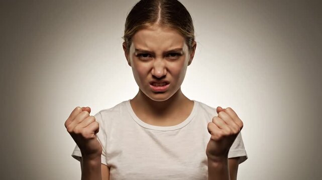 A young girl displays anger and frustration, clenching fists and making aggressive facial expressions in a series of shots with neutral background.