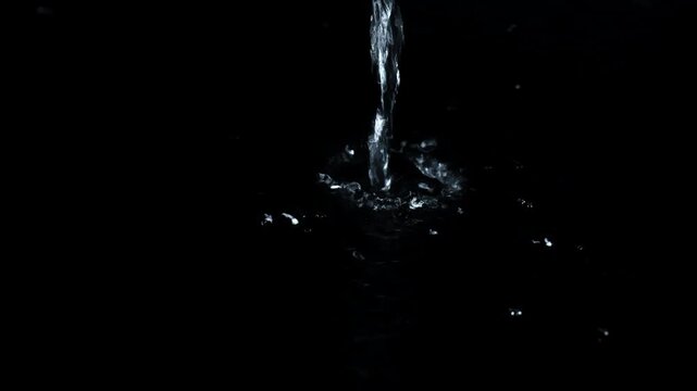 Pouring water with drops on a dark background. 4K video.