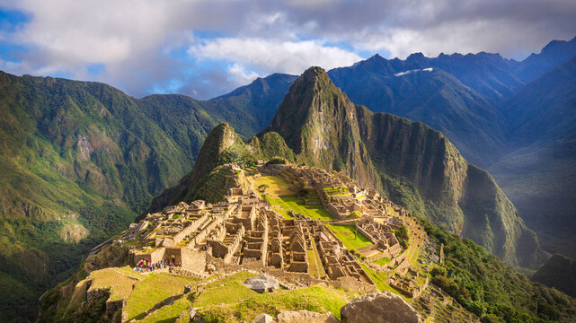 Ancient Inca citadel of Machu Picchu at sunrise with Huayna Picchu mountain in the background. Stone ruins and terraces of the archaeological site in the Andes Mountains of Peru.