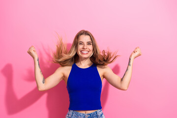 Young woman in blue top celebrates with joy against pink background for fashion lifestyle...