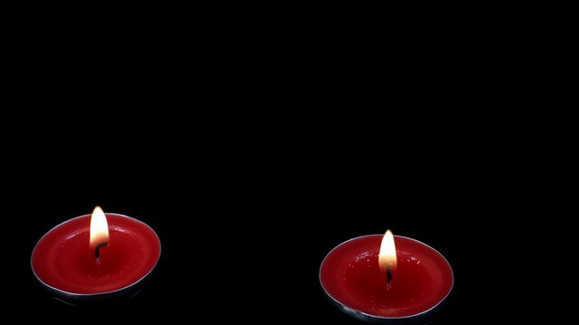 Red scented candles float slowly in the water, creating a beautiful scene on a black backdrop. 4K video