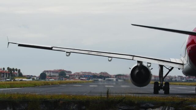 Closeup of a commercial jet airplane engine powering up for takeoff on a wet runway. The powerful thrust kicks up a large spray of water and mist into the air. Overcast day