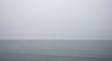 Vast ocean meeting a barely discernible horizon line under a misty, overcast sky