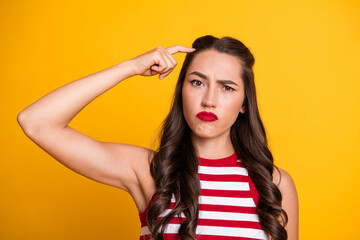 Fototapeta premium Young brunette model in striped top with puzzled expression against yellow background showcasing fashion style and lifestyle