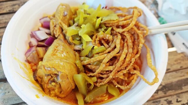 Khao Soi Gai, Northern Thai coconut curry noodle soup with chicken drumstick.