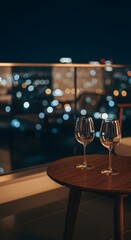 Fototapeta premium Two wine glasses on a balcony overlooking a blurred city skyline at night