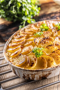 Golden-brown gratin potatoes, neatly arranged in a white ceramic bowl and garnished with fresh herbs. In Slovakia, however, this dish is known primarily at home as French potatoes