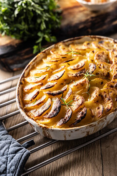Golden-brown gratin potatoes, neatly arranged in a white ceramic bowl and garnished with fresh herbs. In Slovakia, however, this dish is known primarily at home as French potatoes