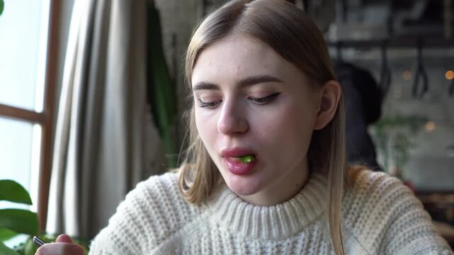 young beautiful woman eats borscht with spoon in cafe, girl eats soup with lard and bread in restaurant, close-up