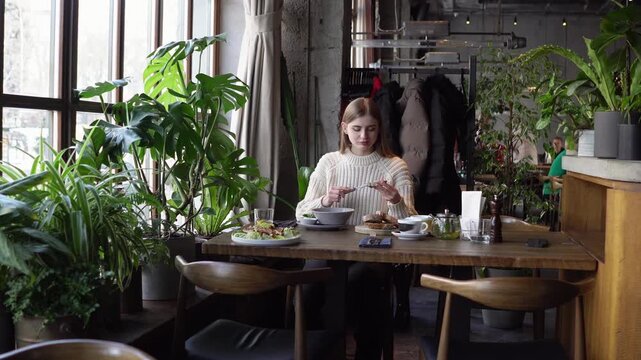 young beautiful woman spreads butter on bread in cafe, girl eats Ukrainian borscht with lard and bread in restaurant