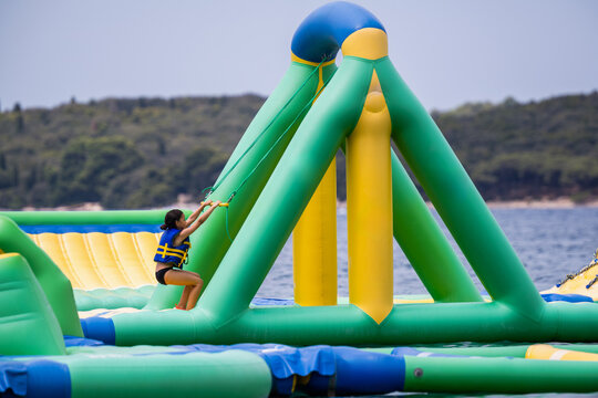 Woman climbing inflatable water park during summer vacation